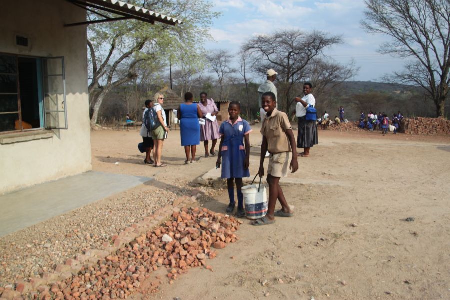 After breaking up the bricks, the kids haul them over and spread them as landscaping in their schoolyard